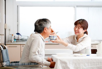介護スタッフが高齢の男性に食事の介助をしている様子
